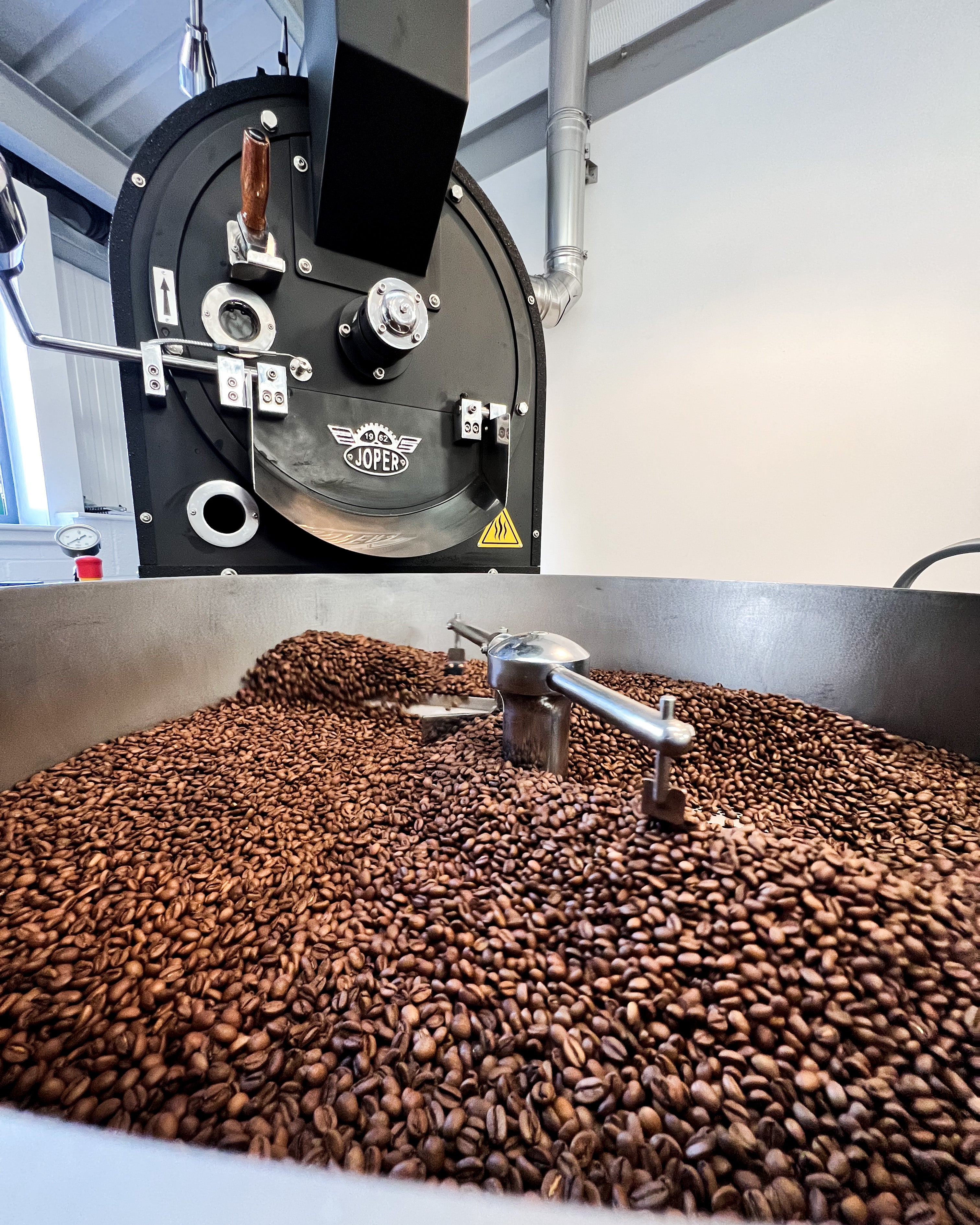 A black Joper coffee roaster with the beans in the cooling tray.