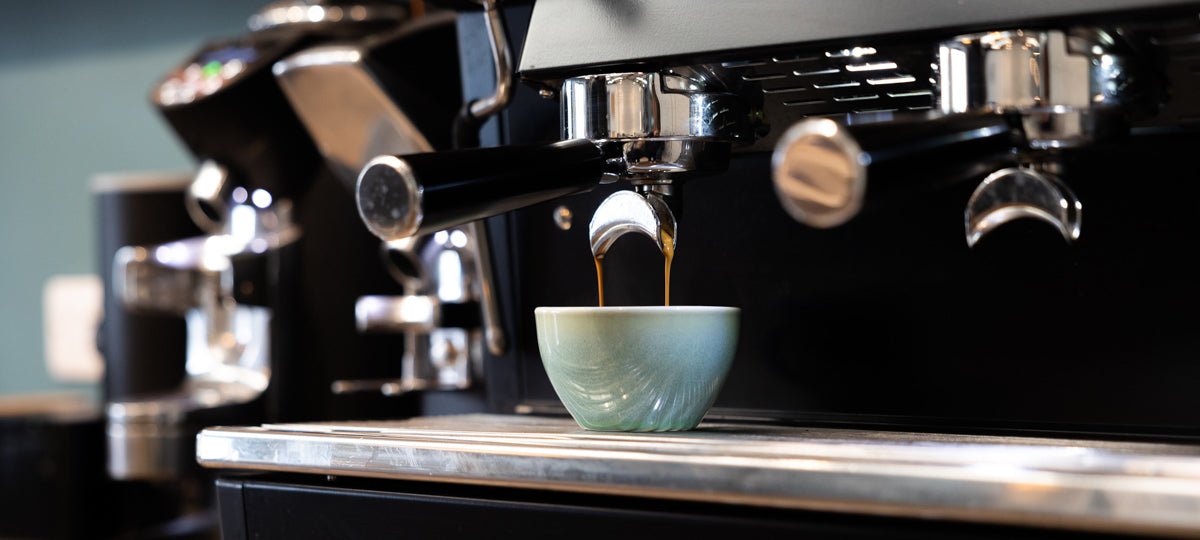 A professional espresso machine with espresso being pulled into a cup.