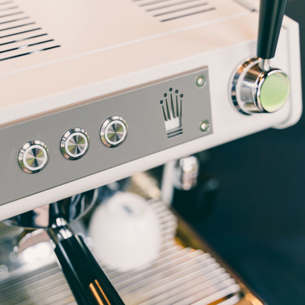 A close up image of the conti ace espresso machine buttons and conti logo