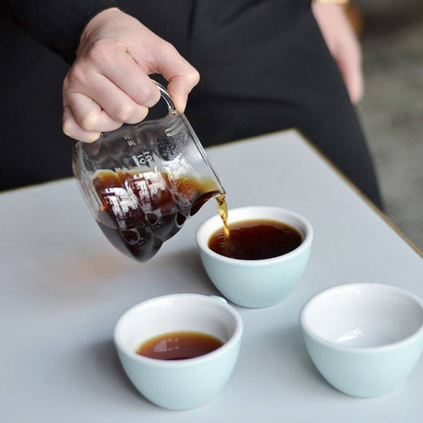 A Hario V60 360ml Range Server pouring coffee into three white mugs