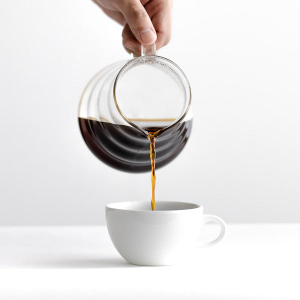 A Hario V60 360ml Range Server in glass, pouring coffee into a white cup